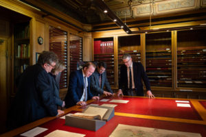 Group of people examining documents in the archive