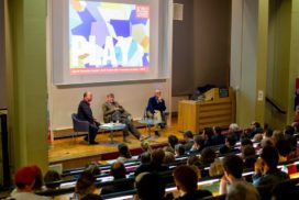 Lecture by three scholars on stage in front of audience