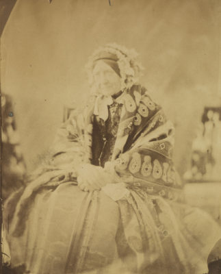 Three quarters length albumen print of Mary, seated and wearing a shawl and headress